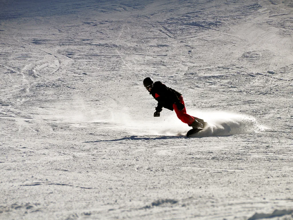 Snowboarder fährt mit aufstiebendem Schnee.
